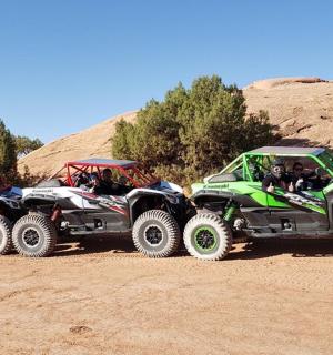 three four wheelers parked on a dirt road