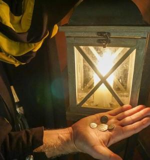 a person with their hand in front of a lantern