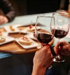 zwei Personen halten Gläser Rotwein