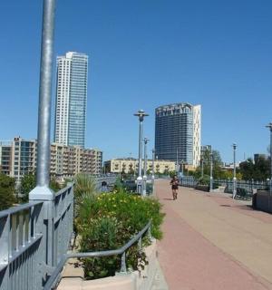 osoba jdoucí po chodníku ve městě s vysokými budovami