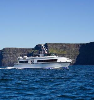 a white boat on the water with cliffs in the background