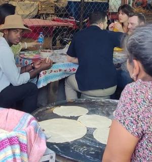 一群人围坐在桌旁做披萨