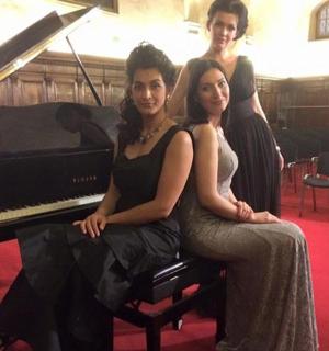 三位身穿黑色连衣裙的女士坐在钢琴上