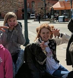 a group of girls sitting on the curb with their hands up