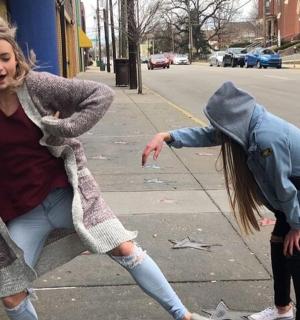 two girls are playing on the sidewalk on the street