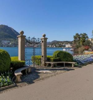 a park with a bench and flowers and a lake