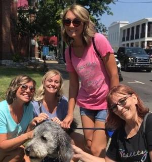 a group of women holding a dog on a leash