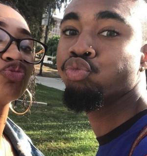 a woman standing next to a man sticking out his tongue