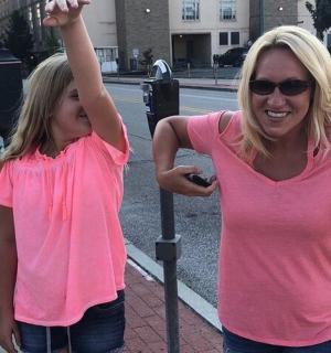 two girls standing next to a parking meter