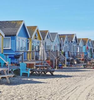 a row of houses on a beach with benches and tables