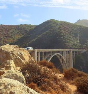a bridge on a mountain with mountains in the background