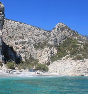 ein Strand neben einem Berg mit Menschen darauf