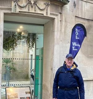 一名男子站在建筑物前，手里拿着冲浪板