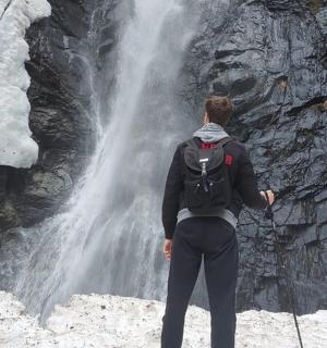 背着背包站在瀑布前的人