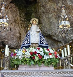 a shrine with a statue and flowers on a altar