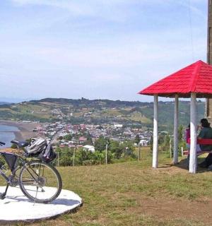 dva lidé sedící na lavičce pod červeným slunečníkem