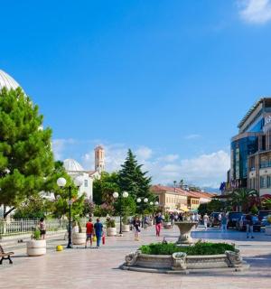 a group of people walking around a city with a building