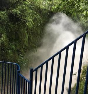 a blue fence next to a gate with a waterfall