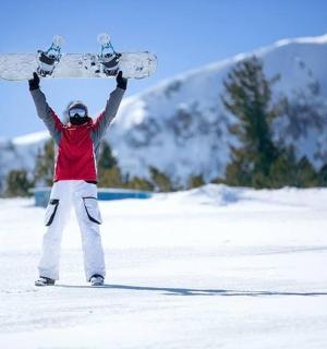 a man holding up a snowboard in the snow