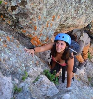 a woman in a helmet climbing on a rock formation