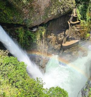 a rainbow over a waterfall with a swing in a river