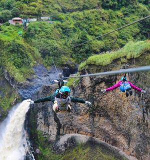 two people on a zip line in front of a waterfall