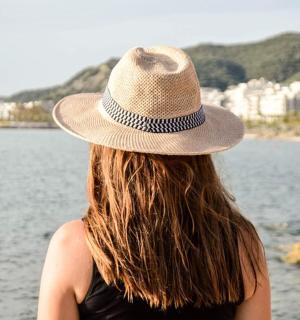 a woman wearing a hat looking at the water