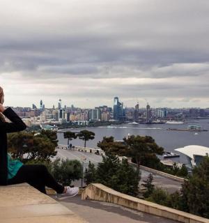 一位女士坐在窗台上眺望城市