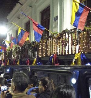 a crowd of people taking pictures of a bus with flags