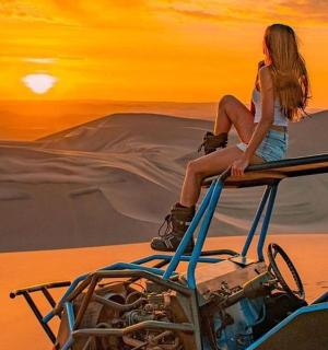 一名女子坐在沙漠中的一辆车顶上