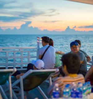 a group of people sitting on a boat in the ocean