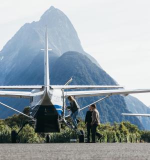 dva lidé stojící vedle malého letadla s horou v pozadí