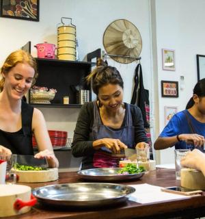 a group of women standing around a table preparing food