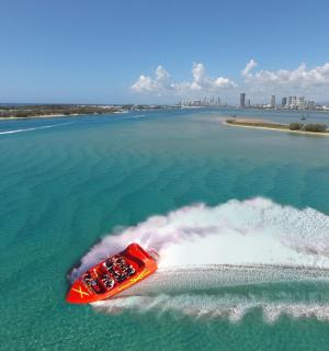 a red boat riding a wave in the water