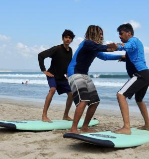 a group of people standing on surfboards on the beach