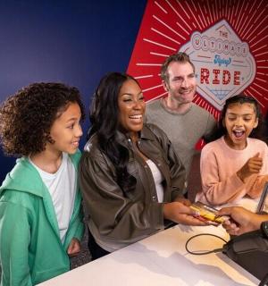 一群人围着桌子站着，桌子上有一台电脑