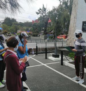 skupina lidí v rouškách stojících na parkovišti