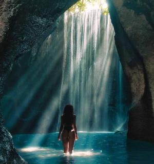 žena stoji u vodi ispred vodopada