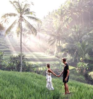 a man and woman standing in a field holding hands