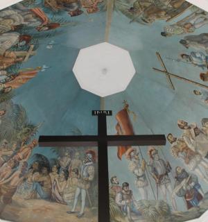 uma cruz no topo de uma parede com uma pintura