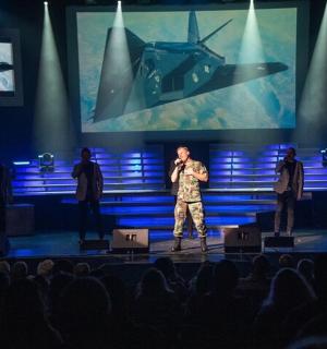 muž stojící na pódiu s mikrofonem