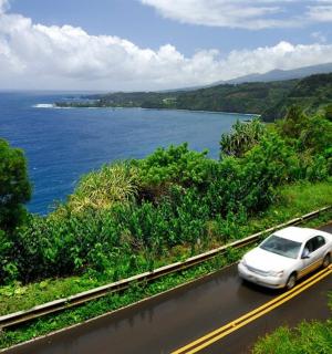 一辆白色汽车沿着海边的道路行驶