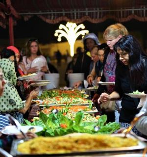 a group of people standing around a table with pizzas