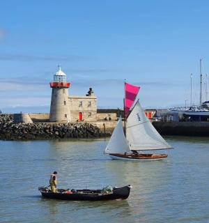 水中有两艘船,背景是一座灯塔