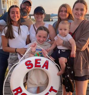 skupina lidí stojící na molu s cedulí