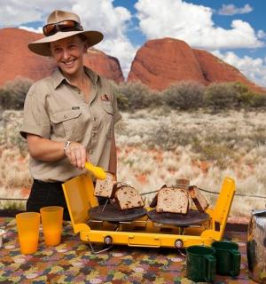 muž v kovbojském klobouku připravující jídlo na grilu