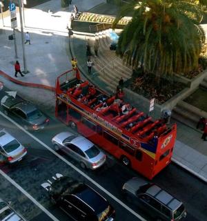 a red double decker bus driving down a street with cars