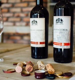 two bottles of wine and a glass of wine