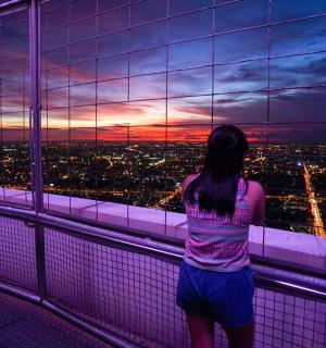 a woman looking out of a window at a sunset