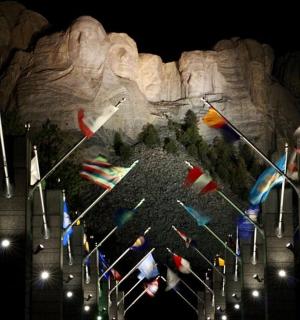 a bunch of flags flying in front of a mountain
